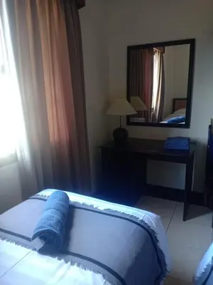 a bedroom with a bed and a desk and a mirror at Kun's Stay Private Apartments in Seminyak