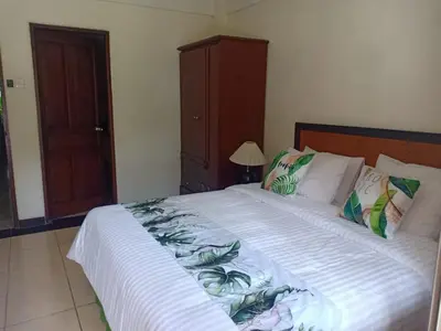 a bedroom with a large white bed with tropical pillows at Kun's Stay Private Apartments in Seminyak
