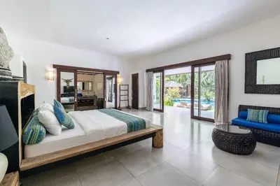 a bedroom with a bed and a blue couch at Villa Permata Umalas - Relaxing Tropical Oasis in Seminyak