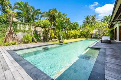 an infinity pool in a villa with palm trees at Villa Ku Besar by Villa Finder in Dalung