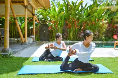 two women sitting in the grass doing yoga at The Open House Jimbaran Bali in Jimbaran