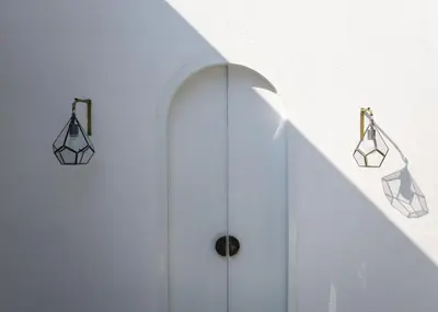 a hallway with a white wall with two lights on it at Villa Weiss Berawa in Canggu