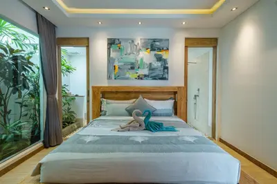 a bedroom with a bed with a stuffed animal on it at Villa Harlow: Stylish 3BR Villa - Centrally Located in Berawa in Canggu