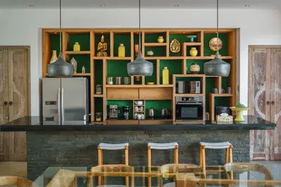 a kitchen with a bar with chairs and a refrigerator at Villa Harlow: Stylish 3BR Villa - Centrally Located in Berawa in Canggu