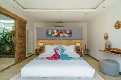 two swans sitting on a bed in a bedroom at Villa Harlow: Stylish 3BR Villa - Centrally Located in Berawa in Canggu