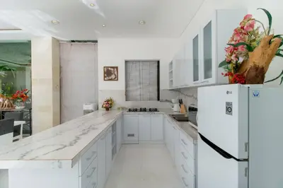 a white kitchen with white cabinets and a refrigerator at Superb 3 Bed Villa, Walk to Beach, Fast Wi-Fi, in Seminyak