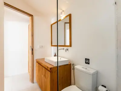 a bathroom with a sink and a toilet and a mirror at Berawa Village Suite in Canggu