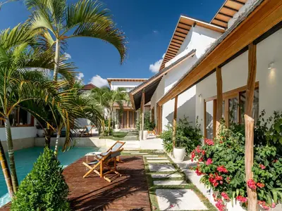 a resort with a swimming pool and palm trees at Berawa Village Suite in Canggu