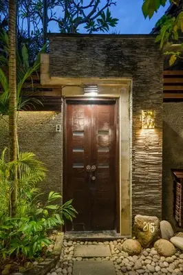 a wooden front door of a house with a light at The Bali Dream Suite Villa Seminyak in Seminyak