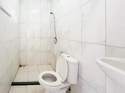 a white bathroom with a toilet and a sink at RedDoorz at Mahendra Beach Inn Kuta in Kuta