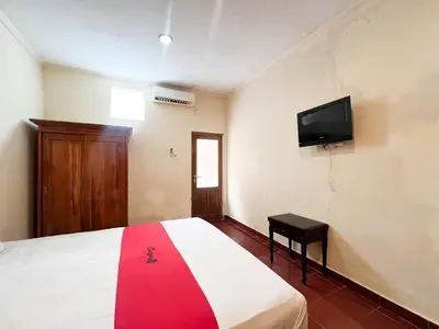 a bedroom with a bed and a tv on the wall at RedDoorz at Mahendra Beach Inn Kuta in Kuta