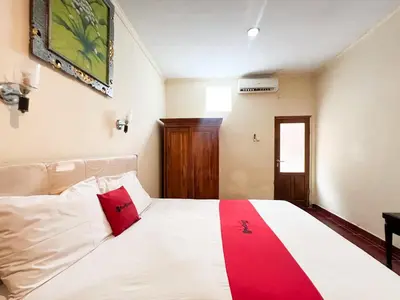 a bedroom with a bed with a red pillow on it at RedDoorz at Mahendra Beach Inn Kuta in Kuta