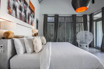 a bedroom with a white bed and a chair at Villa Xaloc by House of Winds - Stunning Balinese retreat next to Canggu in Kerobokan
