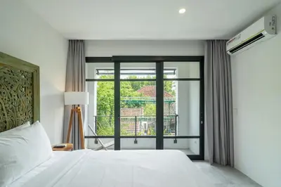 a bedroom with a white bed and a large window at Umalas Living Villa in Canggu