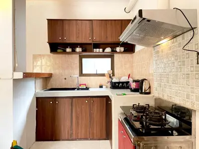 a kitchen with wooden cabinets and a stove top oven at Satran Villa @ Kuta Bali in Legian