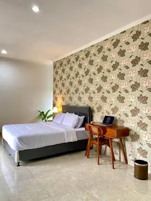 a bedroom with a bed and a desk with a laptop at Satran Villa @ Kuta Bali in Legian