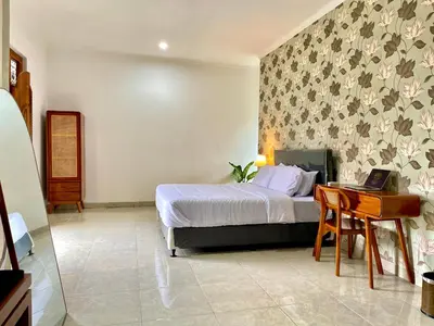 a bedroom with a bed and a desk with a laptop at Satran Villa @ Kuta Bali in Legian