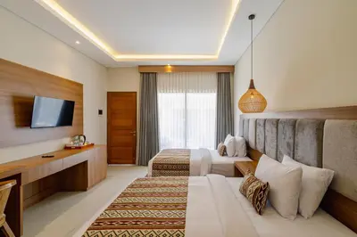 a hotel room with two beds and a television at Casa Wina Kuta by The Wina Resorts in Kuta