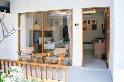 a balcony with chairs and a table and a bedroom at Casa Wina Kuta by The Wina Resorts in Kuta