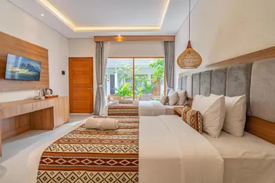 a hotel room with two beds and a television at Casa Wina Kuta by The Wina Resorts in Kuta