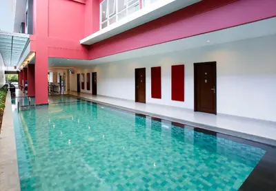 a swimming pool in a building with red and white walls at Amaris Hotel Dewi Sri - Bali in Legian