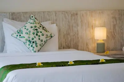 a bed with a green and white blanket and pillows at Fantastic 3 Bed Villa, Walk to Beach, Sunny Pool in Seminyak