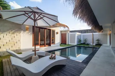 a patio with an umbrella and a swimming pool at Simple & Magical Villas. Villa Sambali llI in Seminyak