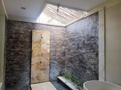 a bathroom with a brick wall with a skylight at Villa alula in Seminyak