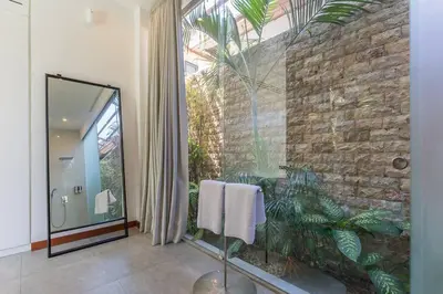 a bathroom with a stone wall and a mirror at Villa Serenity: modern design luxury 12m pool and BBQ in Seminyak