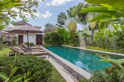 a swimming pool in a garden with lounge chairs and an umbrella at Villa Budha 2 4bedrs 12m Pool, 700m2 garden&BBQ, central & quiet in Seminyak