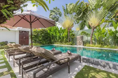 a row of chaise lounge chairs next to a swimming pool at Villa Budha 2 4bedrs 12m Pool, 700m2 garden&BBQ, central & quiet in Seminyak