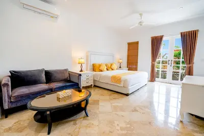 a bedroom with a bed and a couch and a table at Kencana Villa Seminyak in Seminyak