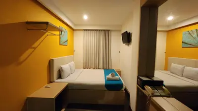 a small room with a bed and a desk at Kimono Spa Hotel in Kuta
