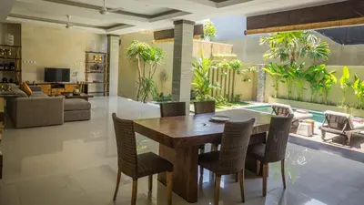 a living room with a wooden table and chairs at The Kumpi Villas in Seminyak