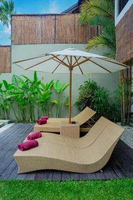 a patio with an umbrella and two pillows and a table at The Kumpi Villas in Seminyak