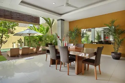 a dining room with a wooden table and chairs at The Kumpi Villas in Seminyak
