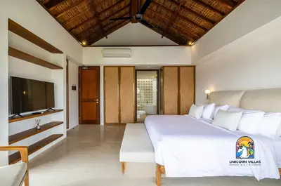 a bedroom with a large white bed and a television at Javine Villa - by Unicorn Villas Bali in Canggu