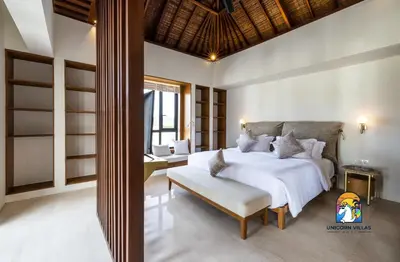 a bedroom with a bed and a bench in a room at Javine Villa - by Unicorn Villas Bali in Canggu