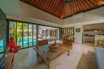 a living room with a wooden table and a pool at Villa Anahata: Modern 2BR Villa w/ Pool in Seminyak ! in Seminyak