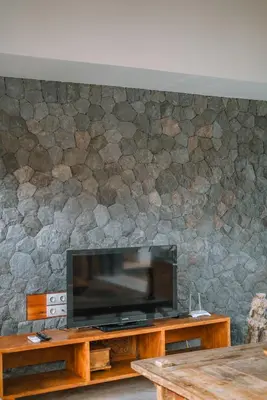 a flat screen tv on a stone wall at Villa Anahata: Modern 2BR Villa w/ Pool in Seminyak ! in Seminyak