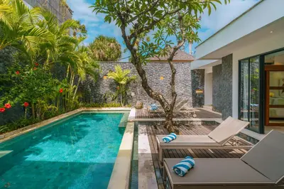 an infinity pool with chairs and a villa at Villa Anahata: Modern 2BR Villa w/ Pool in Seminyak ! in Seminyak