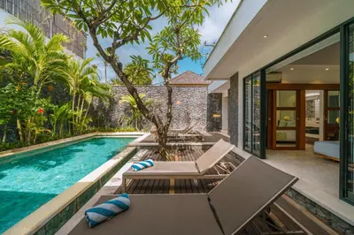 an outdoor pool with a table and chairs next to a house at Villa Anahata: Modern 2BR Villa w/ Pool in Seminyak ! in Seminyak