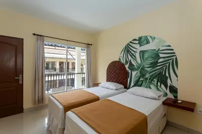 two beds in a room with a large window at Cove Kanaya in Denpasar