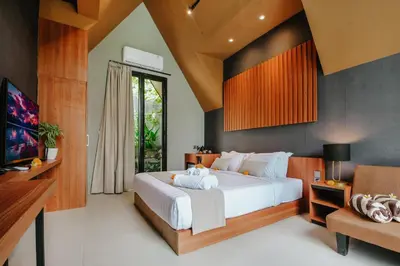 a bedroom with a large white bed and a chair at Le Cielo Resort Umalas by Maviba in Canggu