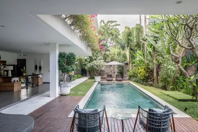 a swimming pool in a backyard with chairs and a table at Villa Alopa 1 in Seminyak