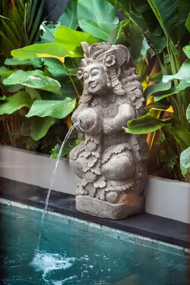a stone statue sitting next to a pool of water at Pondok Arya Kuta Villas by Kamara in Kuta
