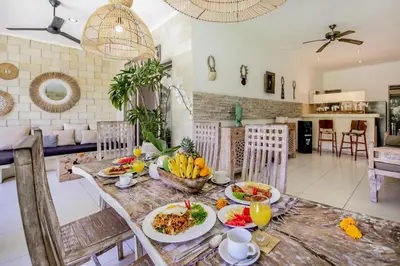 a dining room with a table with food on it at Villa Balissima in Seminyak