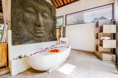 a bath tub with a large head on the wall in a bathroom at Villa Balissima in Seminyak
