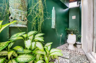 a green wall with a toilet in a room with plants at Villa Balissima in Seminyak