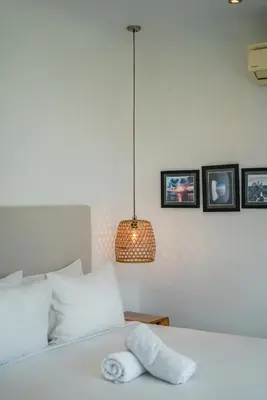 a bedroom with a white bed with a lamp and pictures at Bali Townhouse 1 - Amazing 2BR Villa w/pool - Perfect Location in Canggu